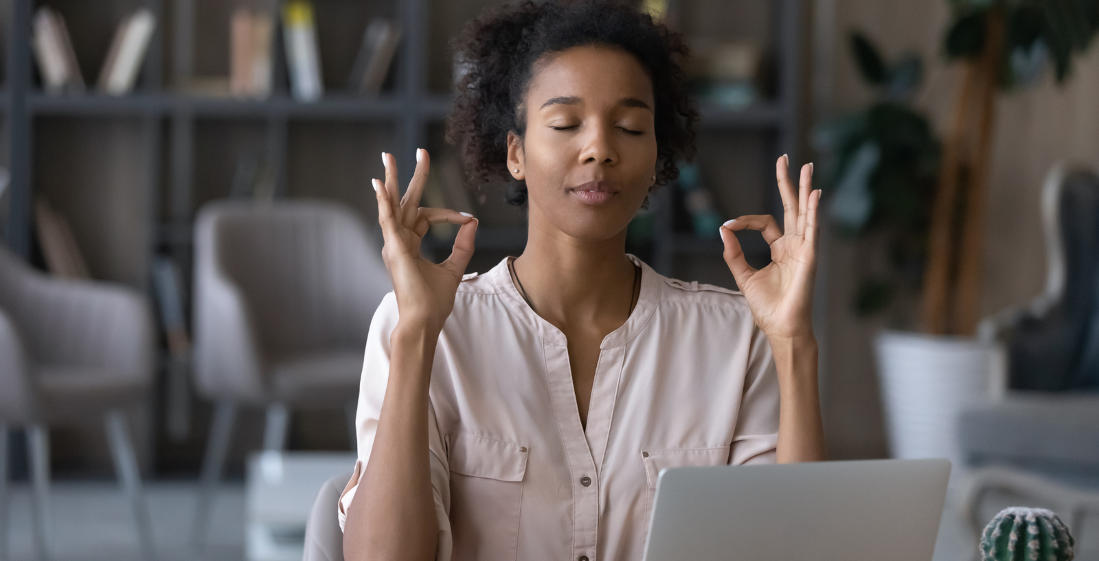 Mulher negra meditando na frente do computador.