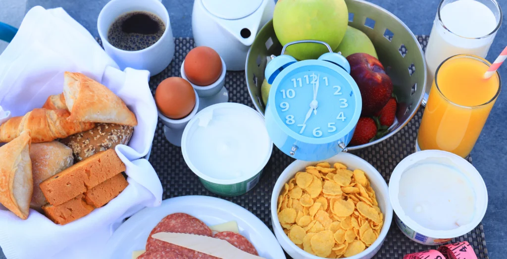 Mesa de comida com um relógio no meio, representando ciclos e dietas intermitentes.